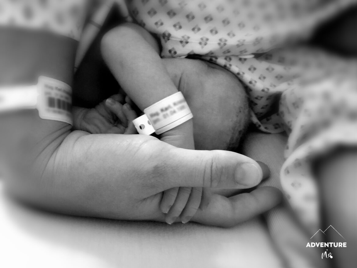 Neugeborenes hält die Hand der Mutter