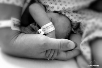 Neugeborenes hält die Hand der Mutter
