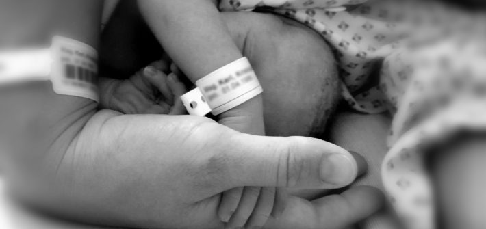 Neugeborenes hält die Hand der Mutter